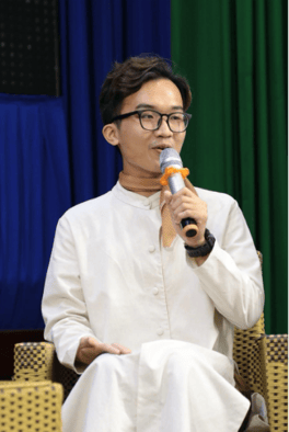 A person in glasses holding a microphone

Description automatically generated