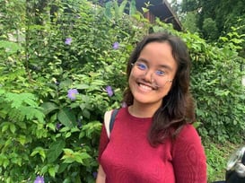 A person smiling in front of plants

Description automatically generated, Picture
