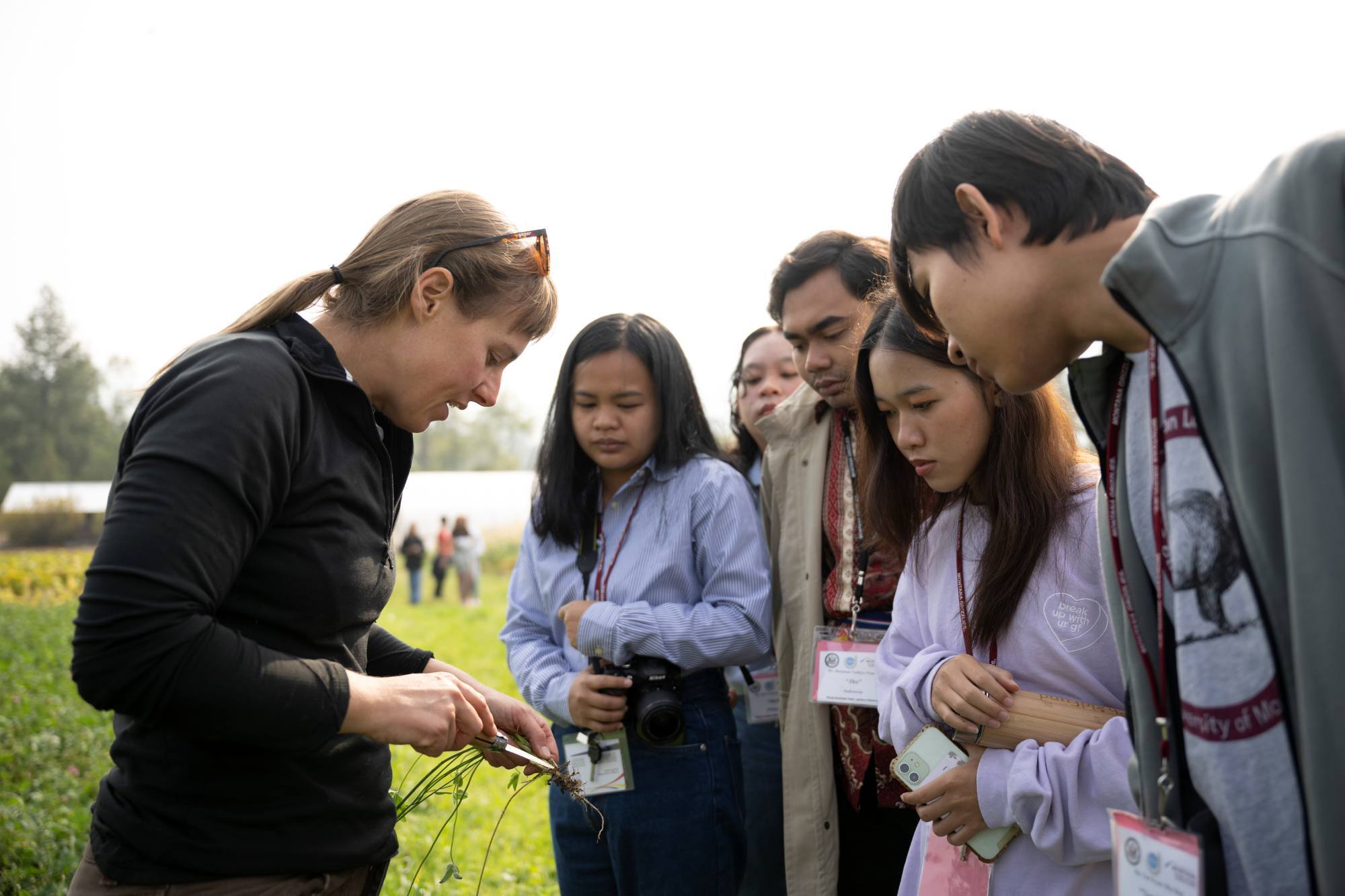 A group of YSEALI participants are standing next to someone looking at an object in their hands