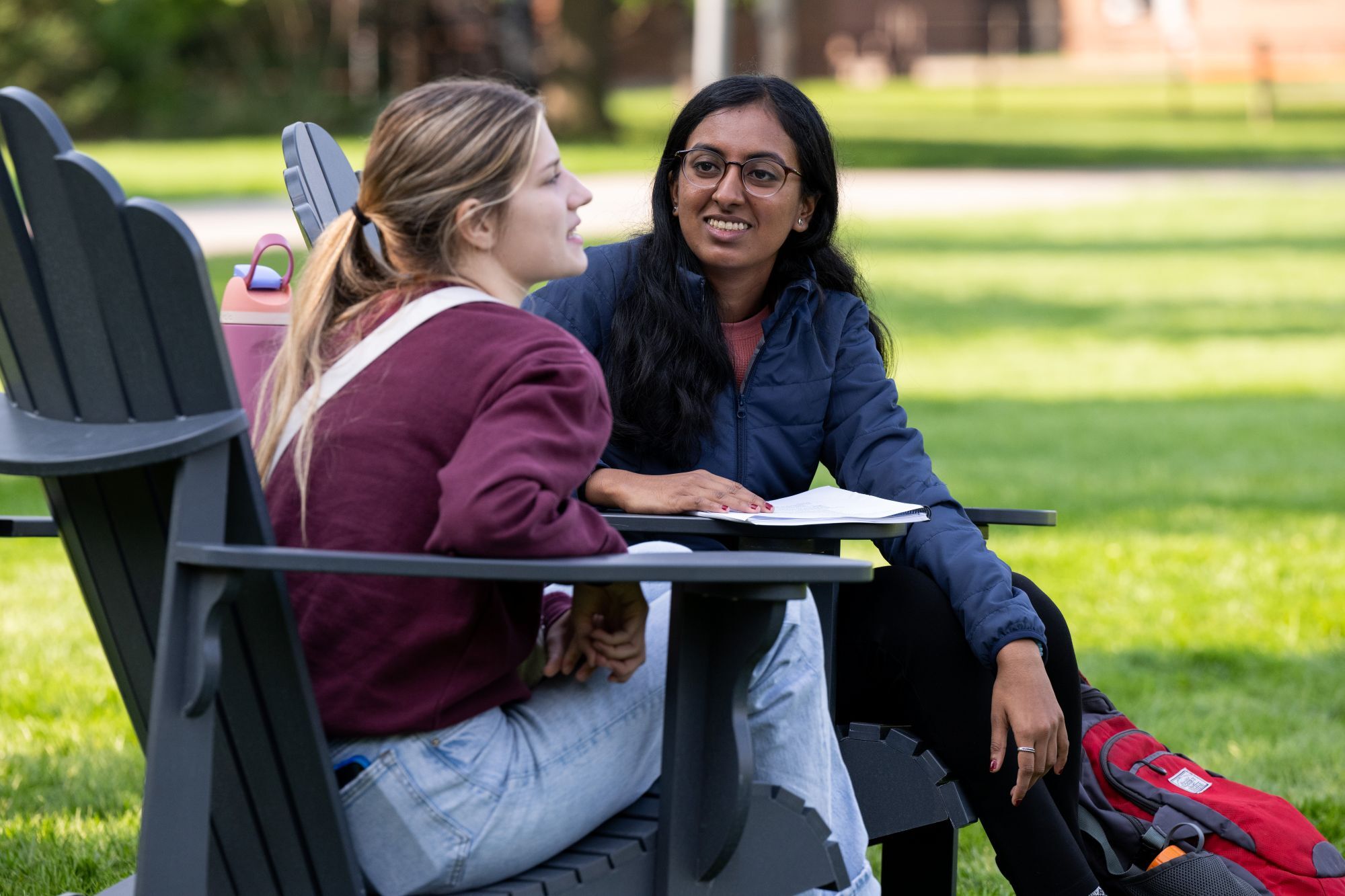 A YSEALI participant talking with someone while sitting in the chairs on the Oval at UM