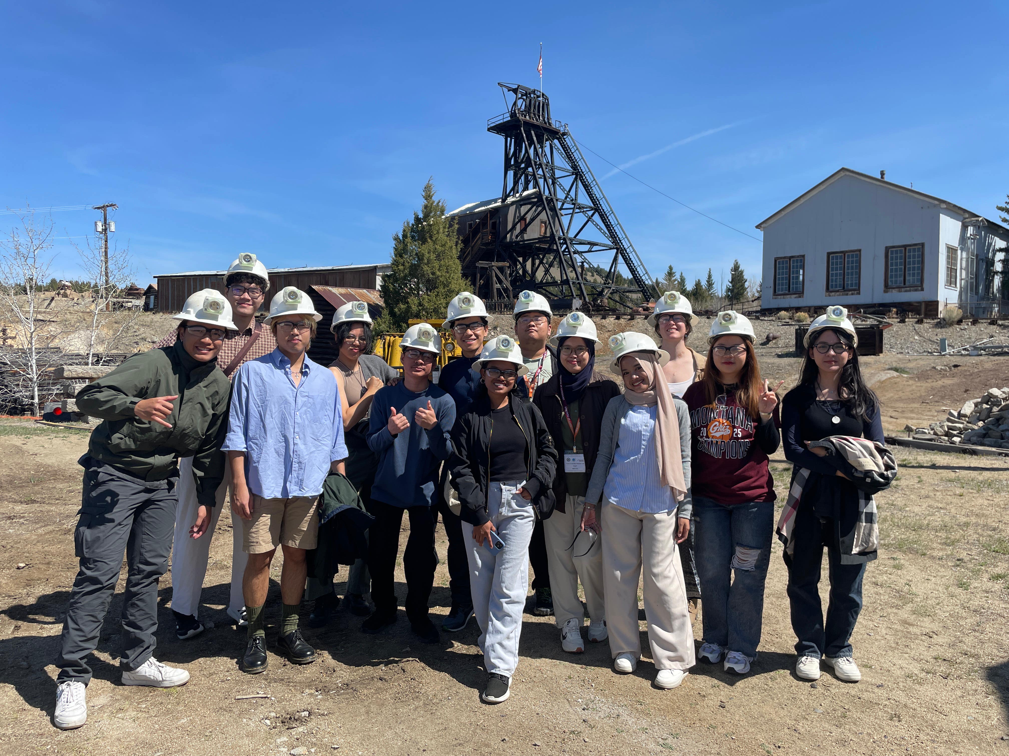 A group of YSEALI participants standing outside a mine while wearing hard hats